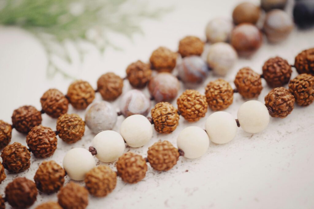 Beautiful close-up of rudraksha and stone beads intricately arranged on a white surface, perfect for meditation themes.